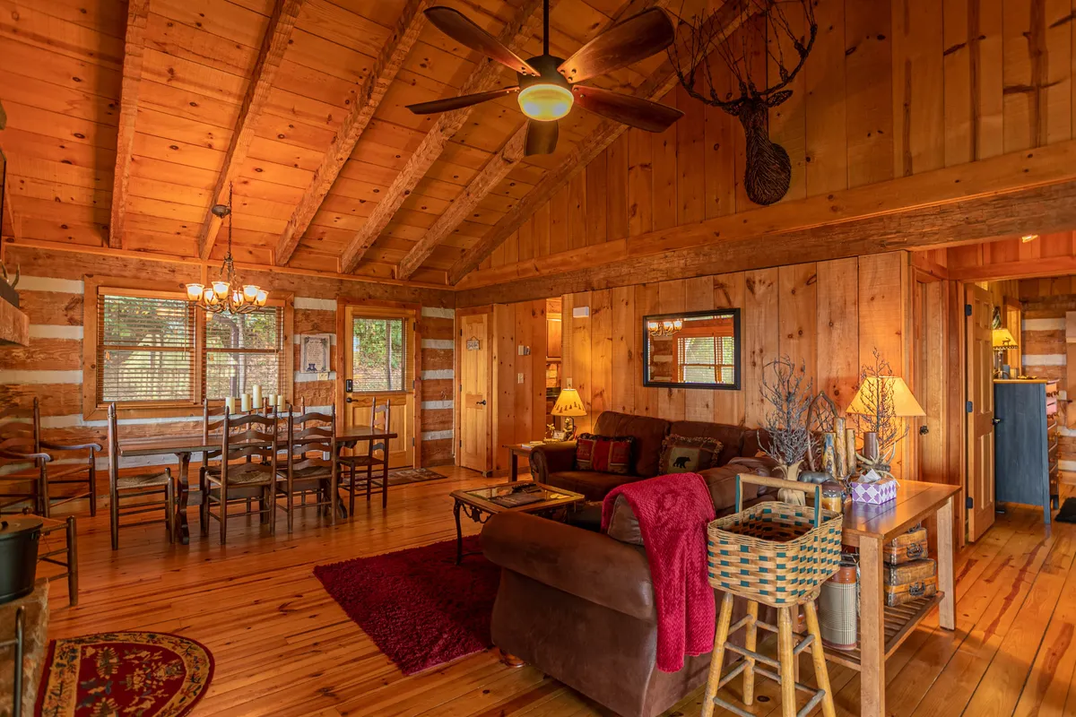 This image captures the heart of the Great Room, featuring soaring wooden beams, a spacious dining table, plush sofa seating, a striking chandelier, and decorative accents. The space feels open and welcoming, ideal for gatherings and celebrations.